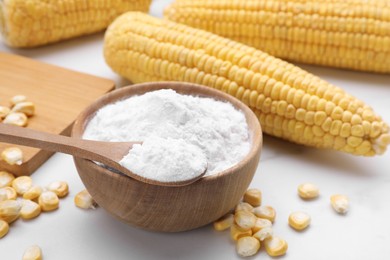 Photo of Bowl with corn starch, ripe cobs and kernels on white table