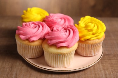 Photo of Delicious cupcakes with bright cream on wooden table, closeup