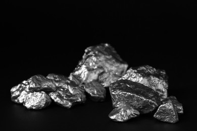 Photo of Pile of silver nuggets on black background, closeup