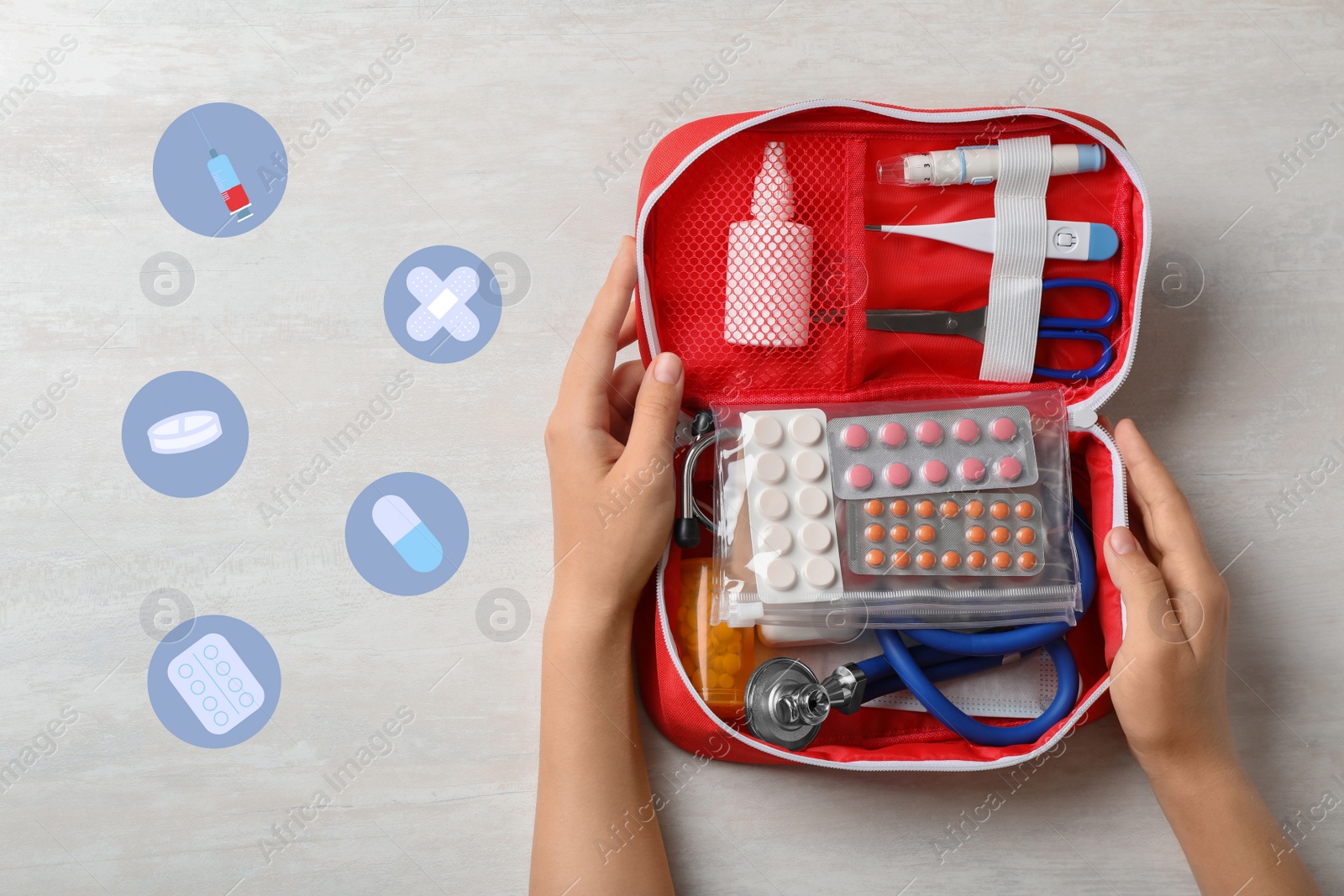 Image of Woman holding first aid kit on white wooden table, top view