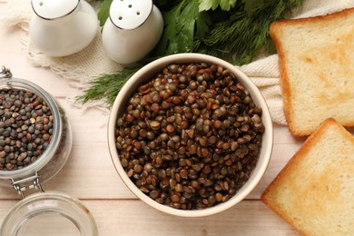 Delicious lentils in bowl served on wooden table, flat lay