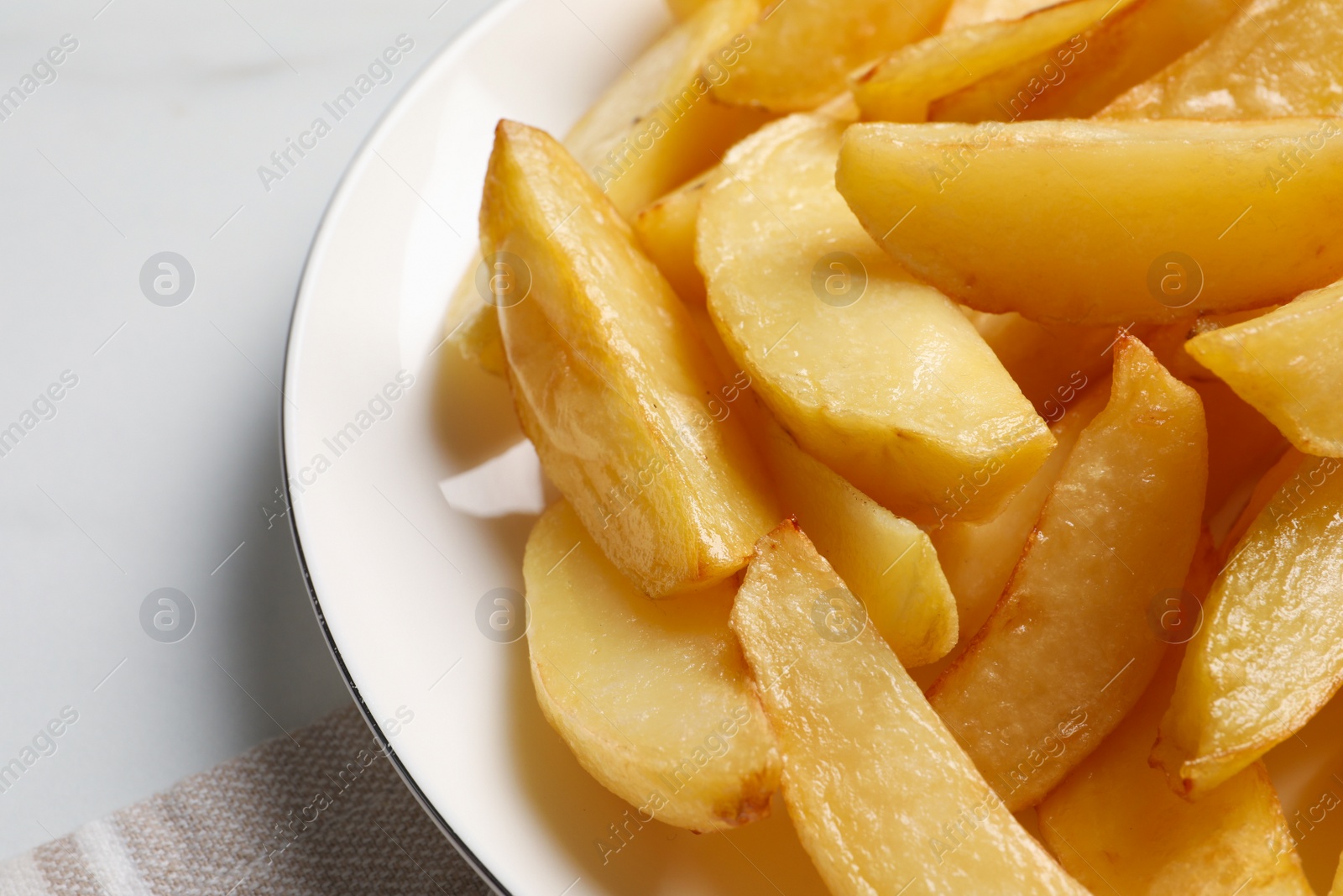 Photo of Plate with tasty baked potato wedges on white table, closeup