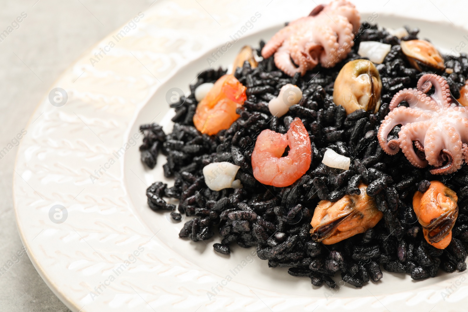 Photo of Delicious black risotto with seafood served on plate, closeup