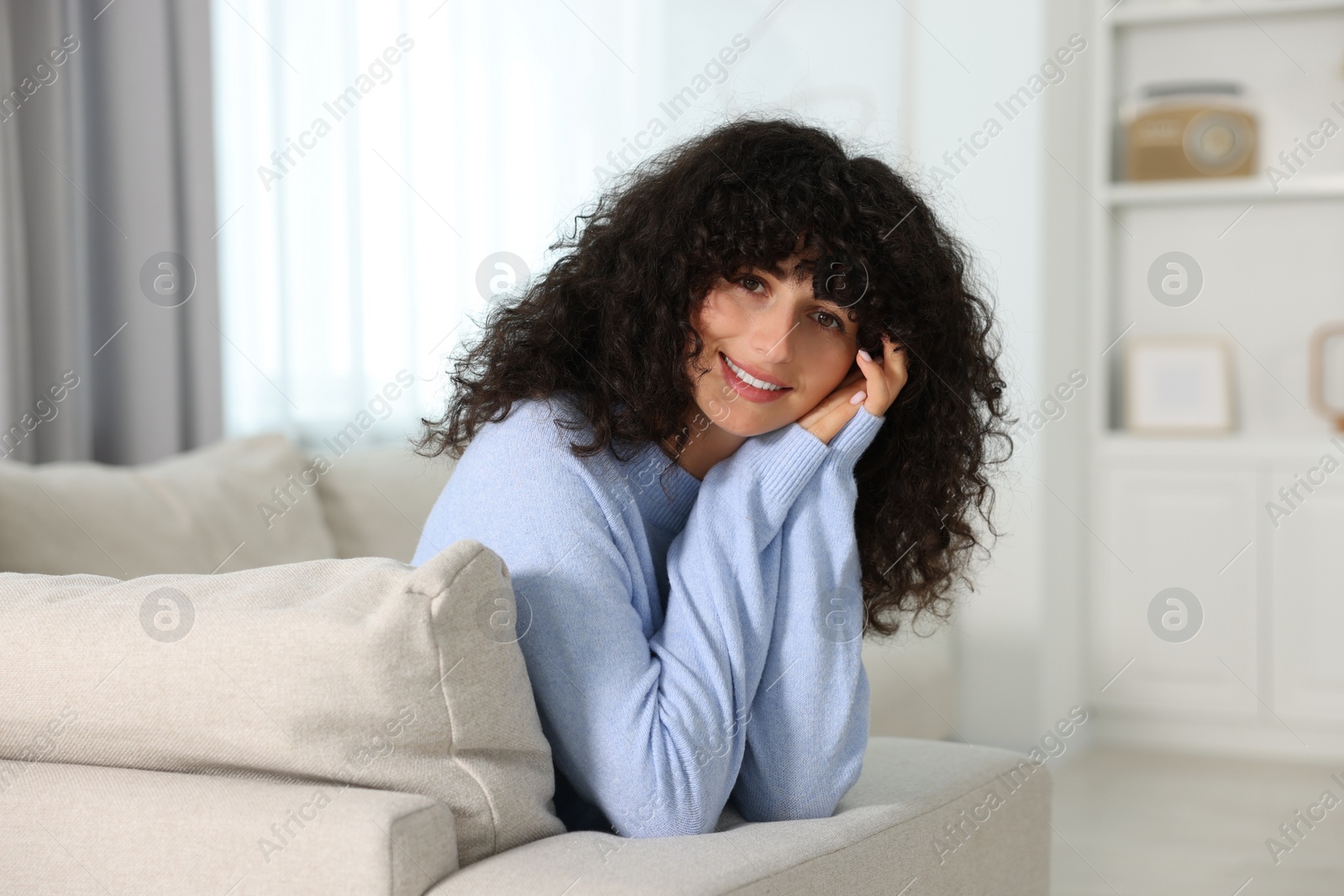 Photo of Happy young woman in stylish light blue sweater indoors