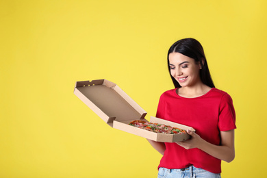 Beautiful woman with tasty pizza on yellow background