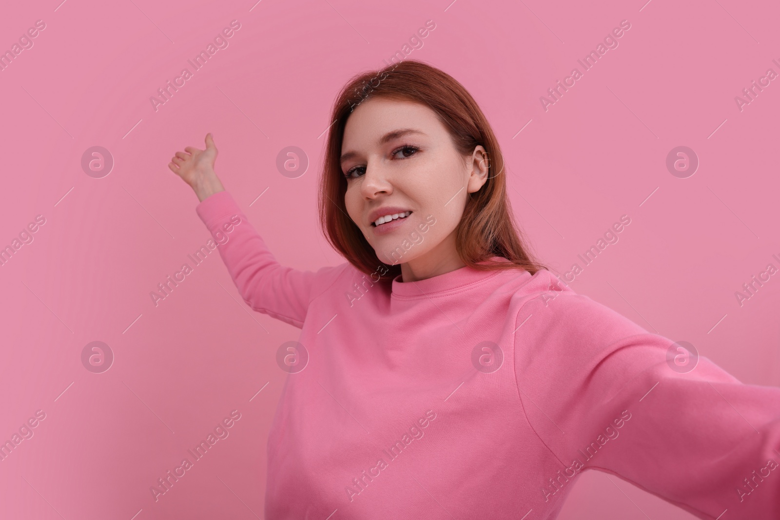 Photo of Beautiful woman taking selfie on pink background