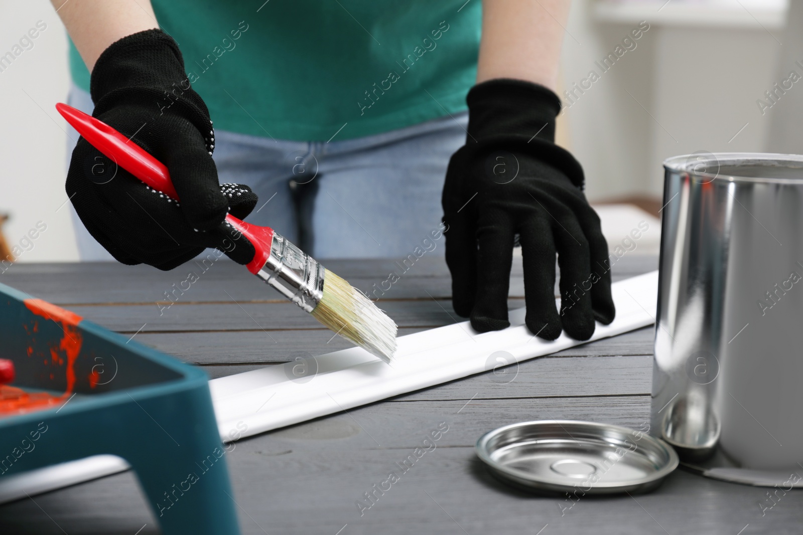 Photo of Woman painting plank with white dye at grey wooden table indoors, closeup