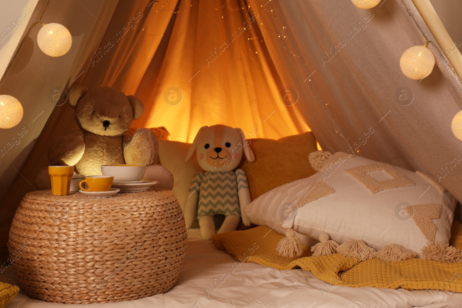 Photo of Play tent with toys and pillows indoors, closeup. Modern children's room interior