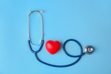 Stethoscope and heart model on color background, top view. Medical equipment