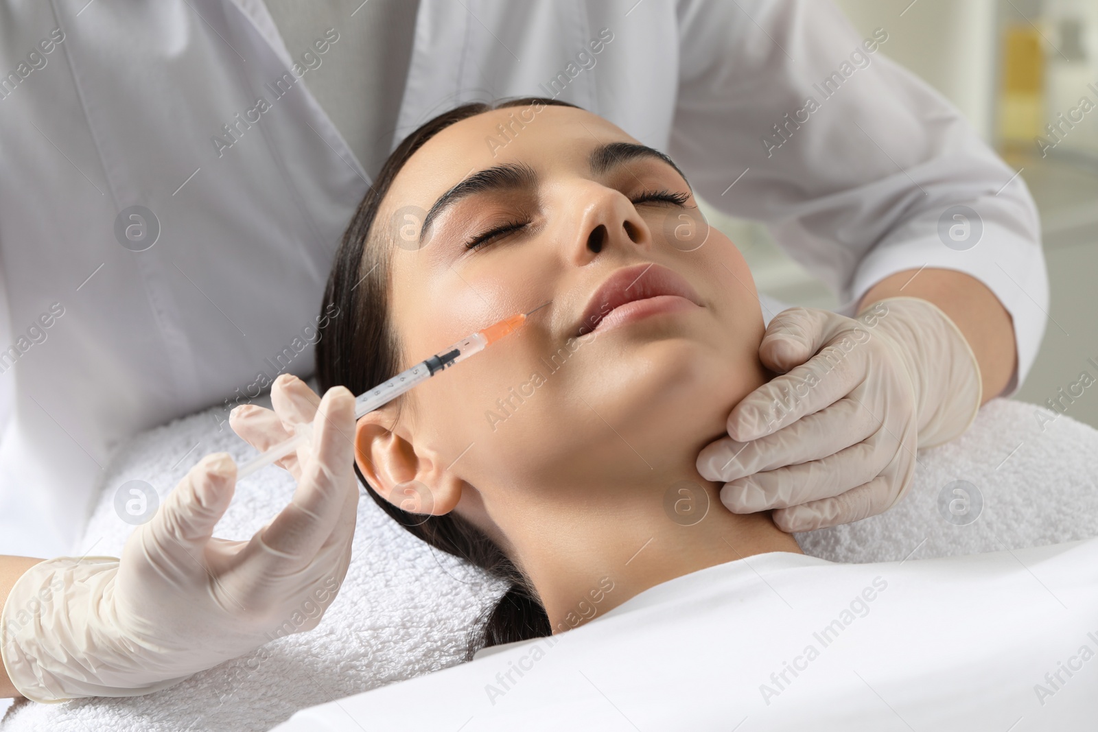 Photo of Doctor giving facial injection to young woman in clinic. Cosmetic surgery