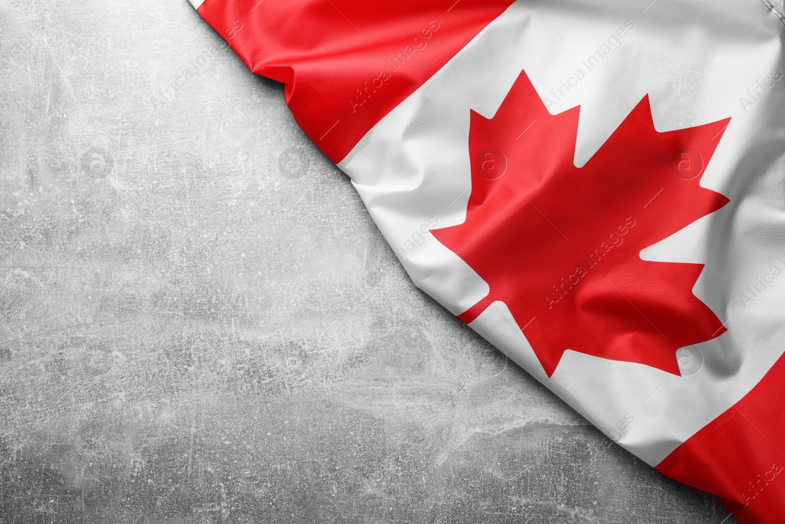 Photo of Flag of Canada on light grey stone table, top view. Space for text