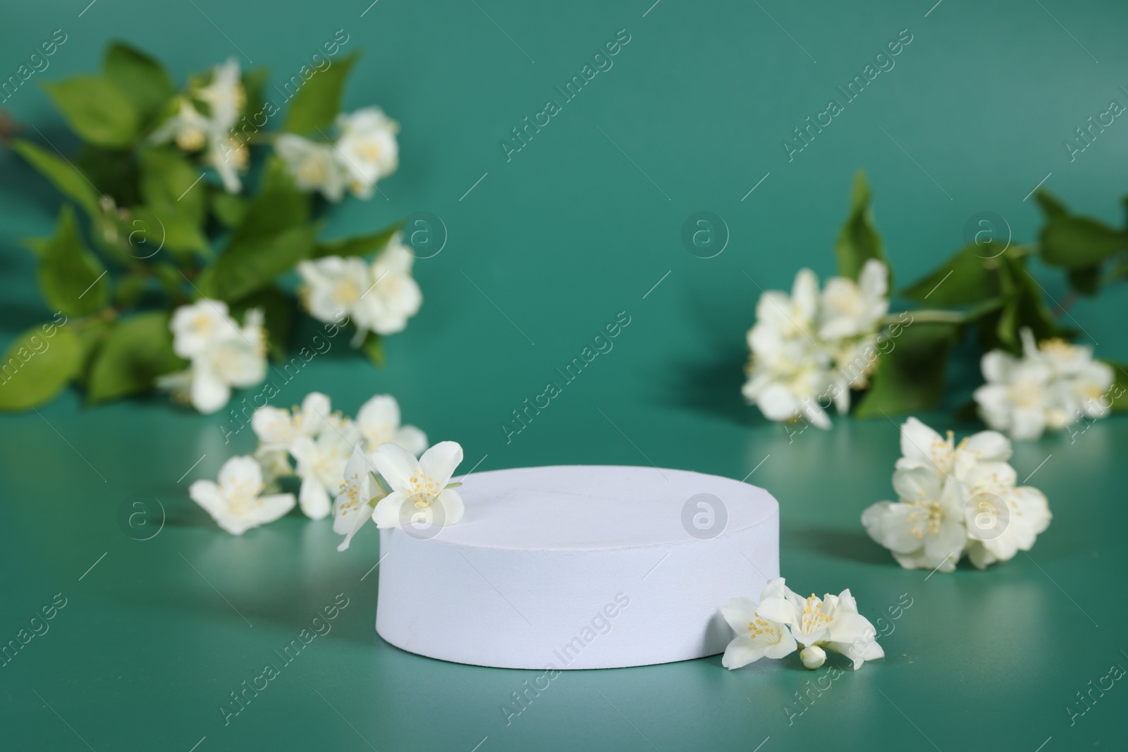 Photo of Presentation of product. White podium and beautiful jasmine flowers on green background