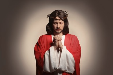 Photo of Jesus Christ with crown of thorns praying on beige background