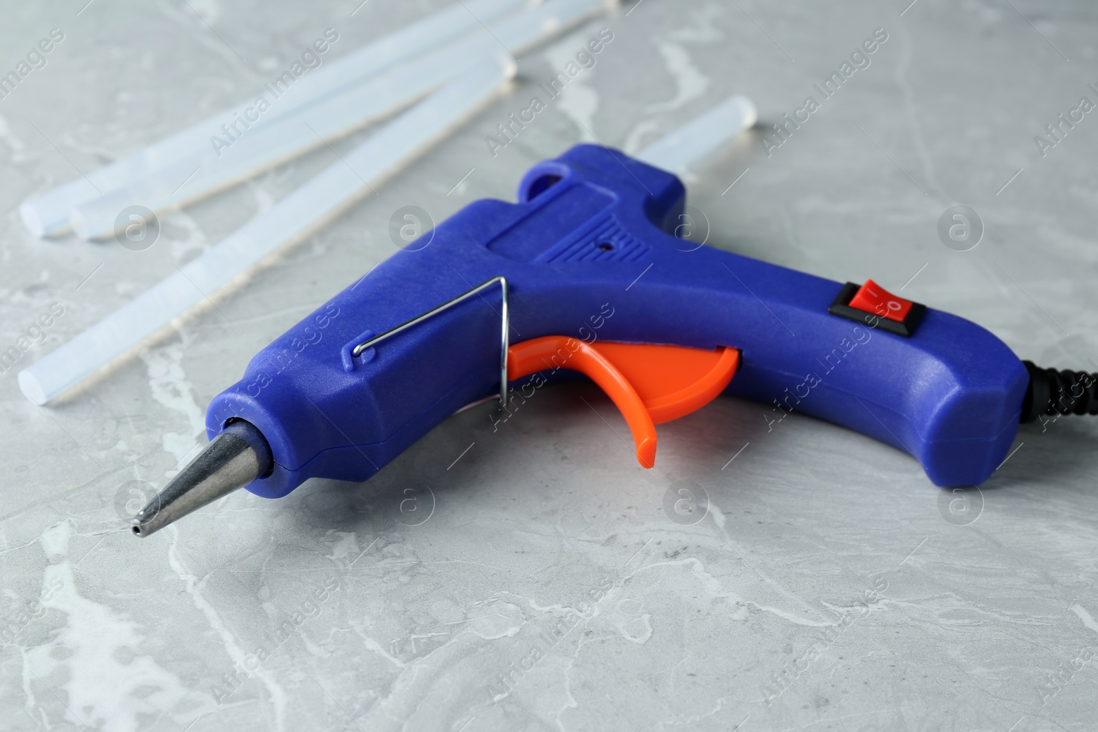 Photo of Hot glue gun and sticks on light grey marble table