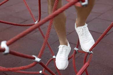 Photo of Man in stylish sneakers standing on training equipment outdoors, closeup