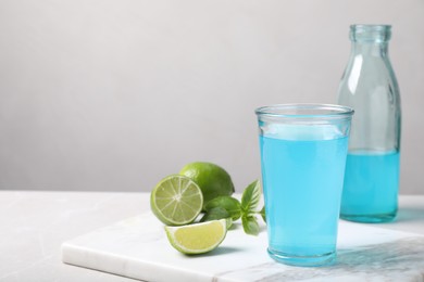 Photo of Refreshing light blue drink on white table, space for text