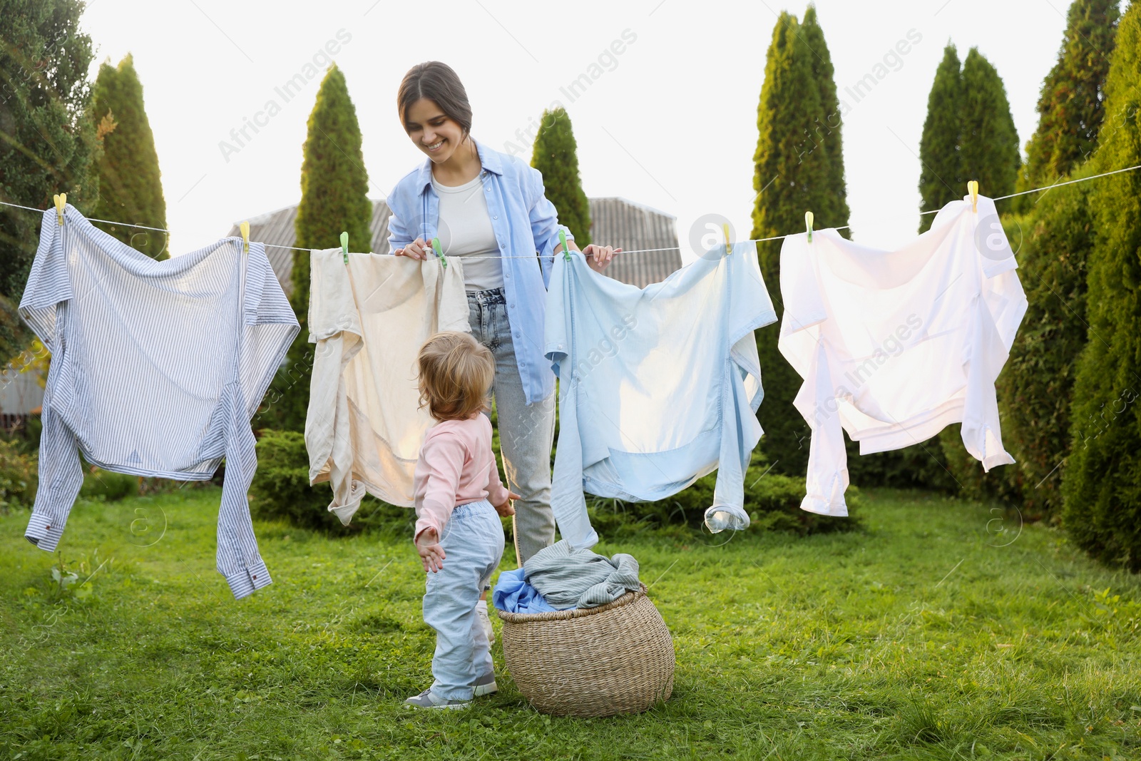 Photo of Mother and daughter near washing line with drying clothes in backyard