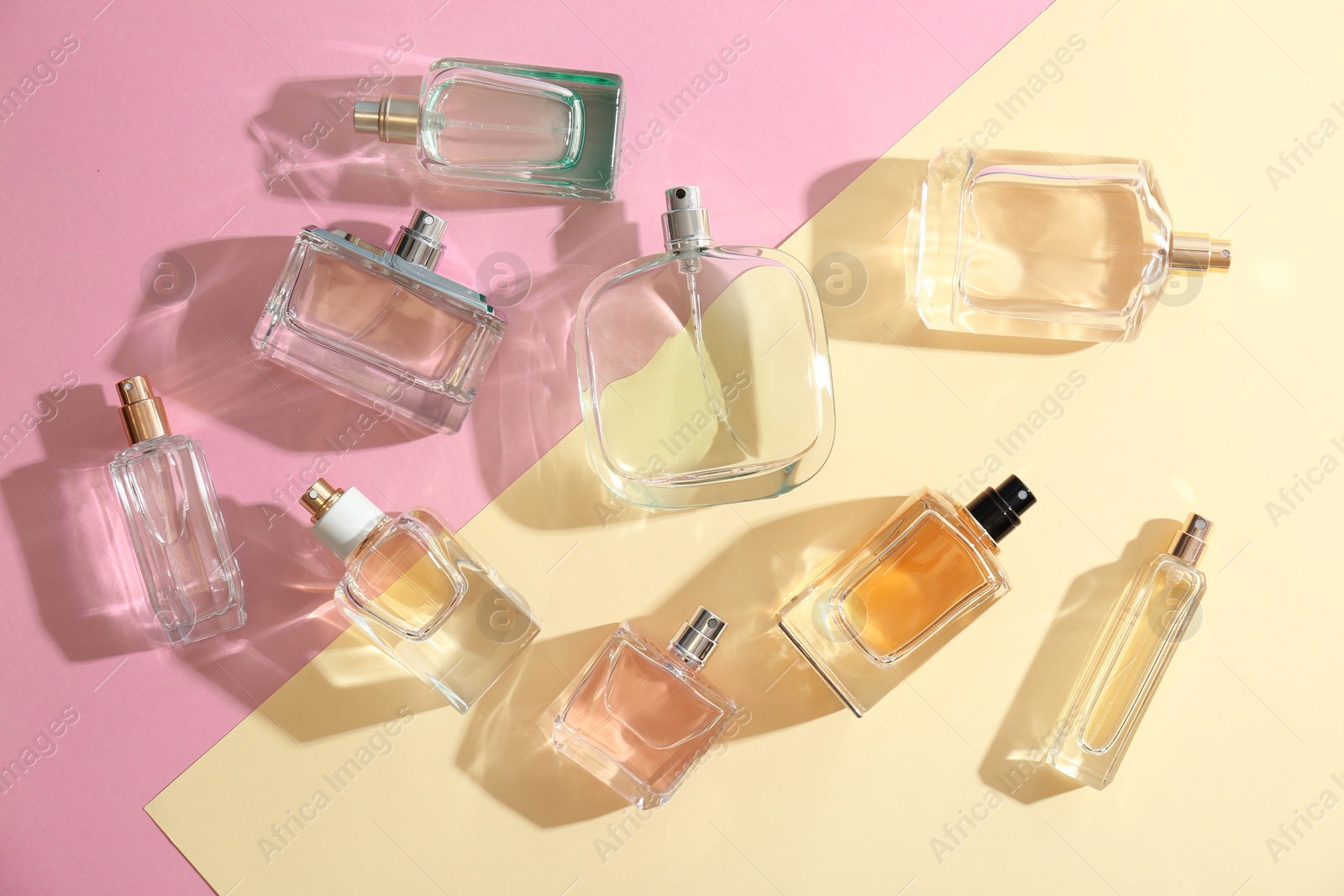 Photo of Perfume bottles on colorful background, flat lay