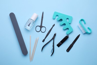 Photo of Set of pedicure tools on light blue background, flat lay