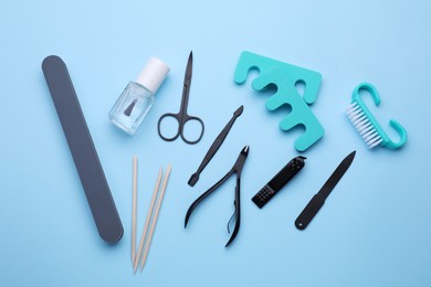 Set of pedicure tools on light blue background, flat lay