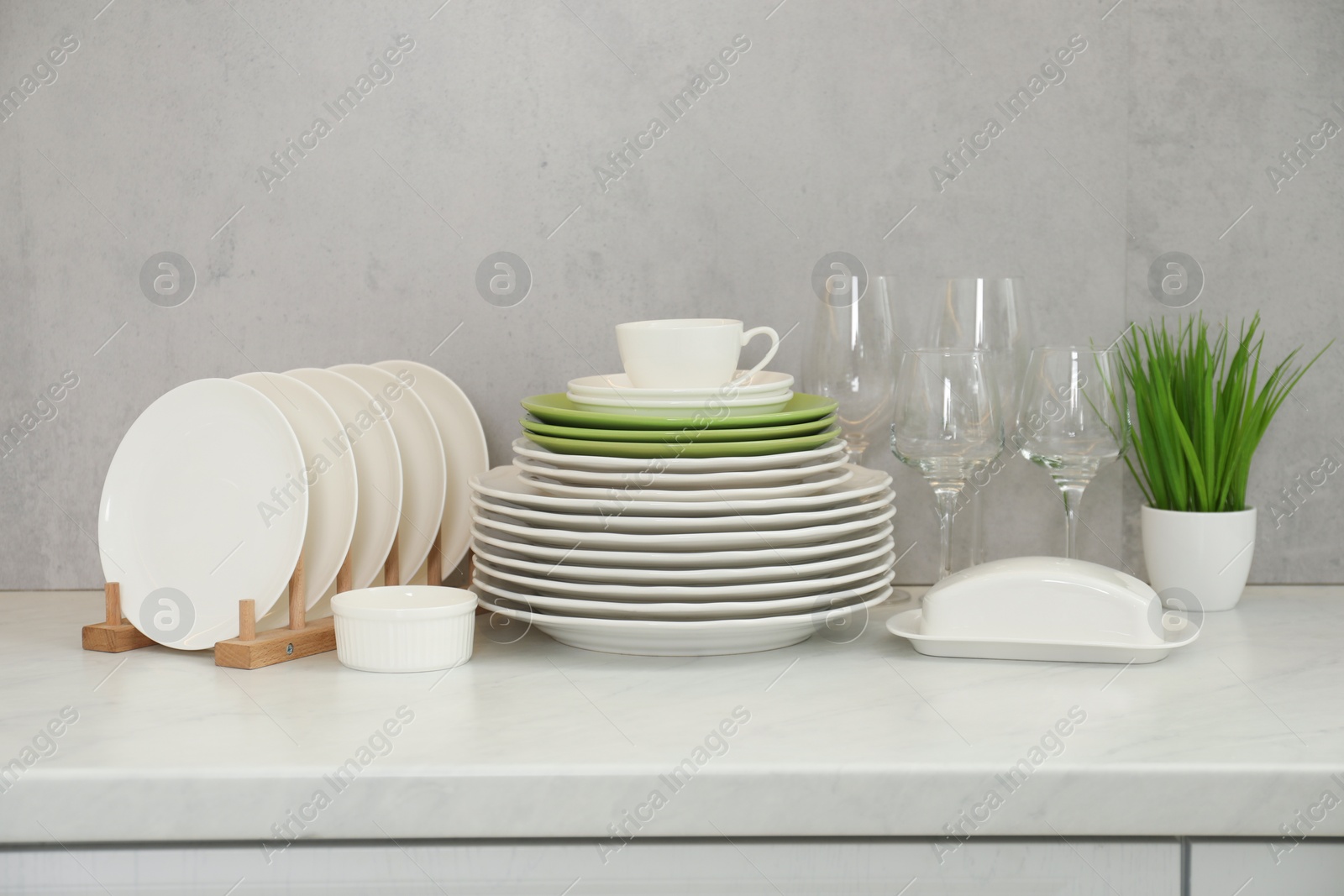 Photo of Clean plates, glasses, cup and floral decor on white marble table