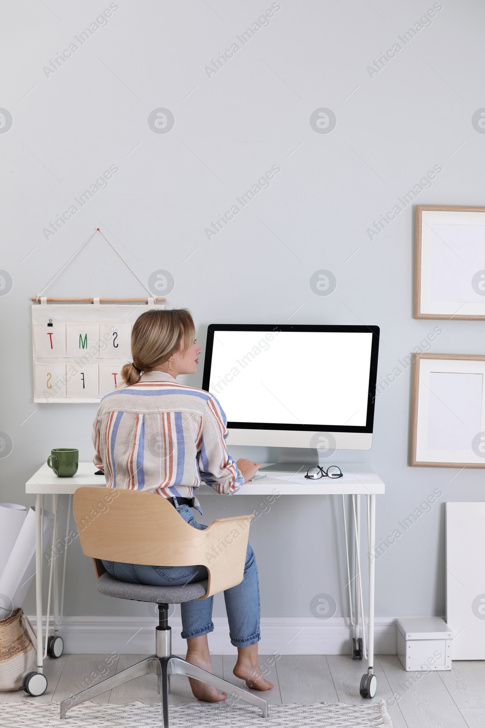 Photo of Young woman working on computer at table in room