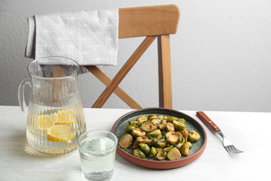 Photo of Delicious roasted brussels sprouts served on white wooden table