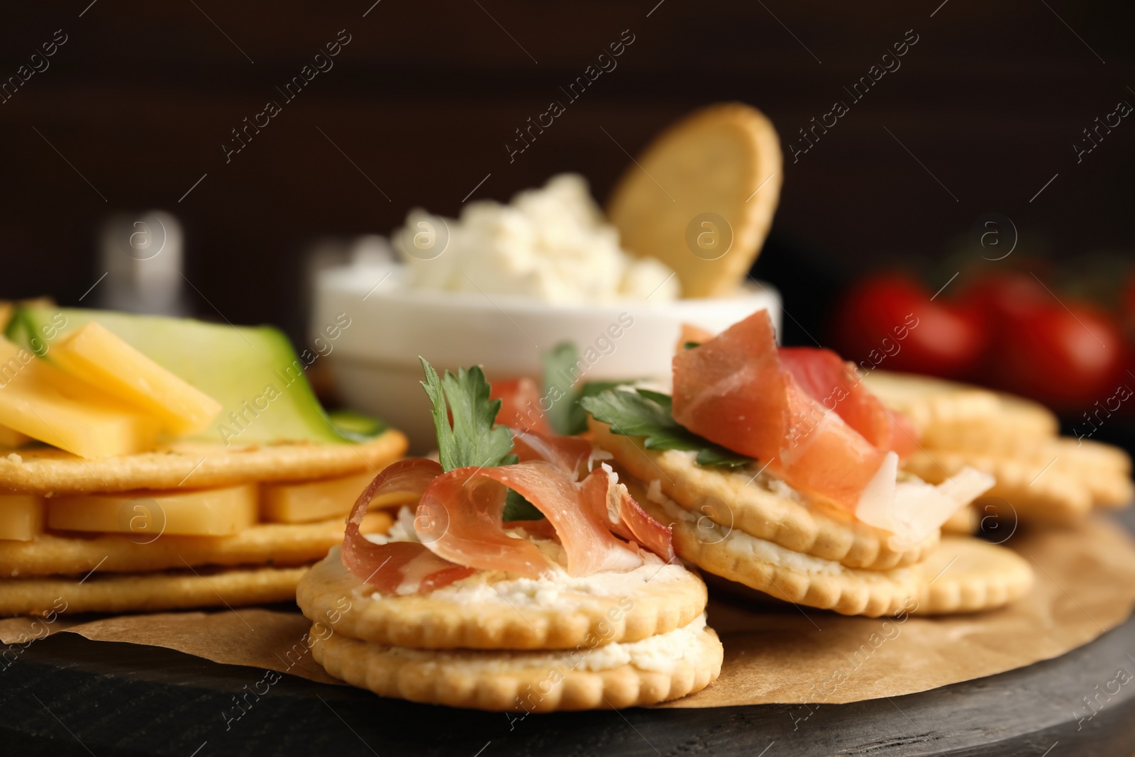 Photo of Different snacks with salted crackers on wooden board, closeup