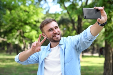 Happy young man taking selfie in park