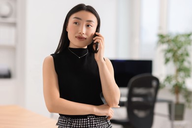 Portrait of beautiful businesswoman talking on smartphone in office