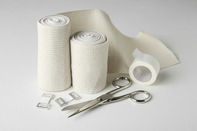 Photo of Medical bandage rolls, sticking plaster and scissors on white table