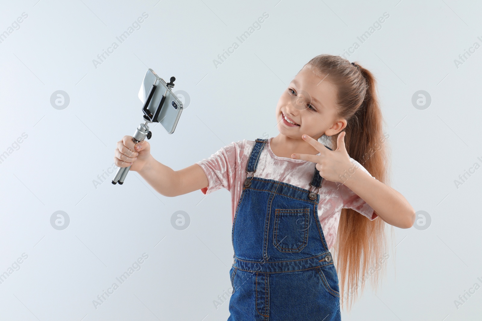 Photo of Cute little blogger recording video on white background