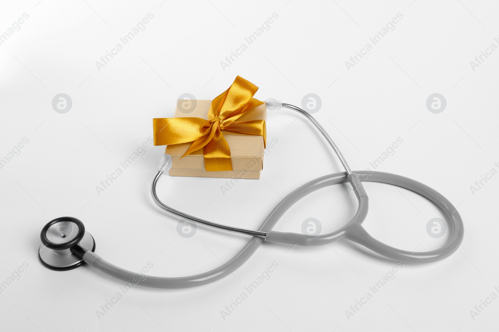 Photo of Stethoscope and gift box on white background. Happy Doctor's Day