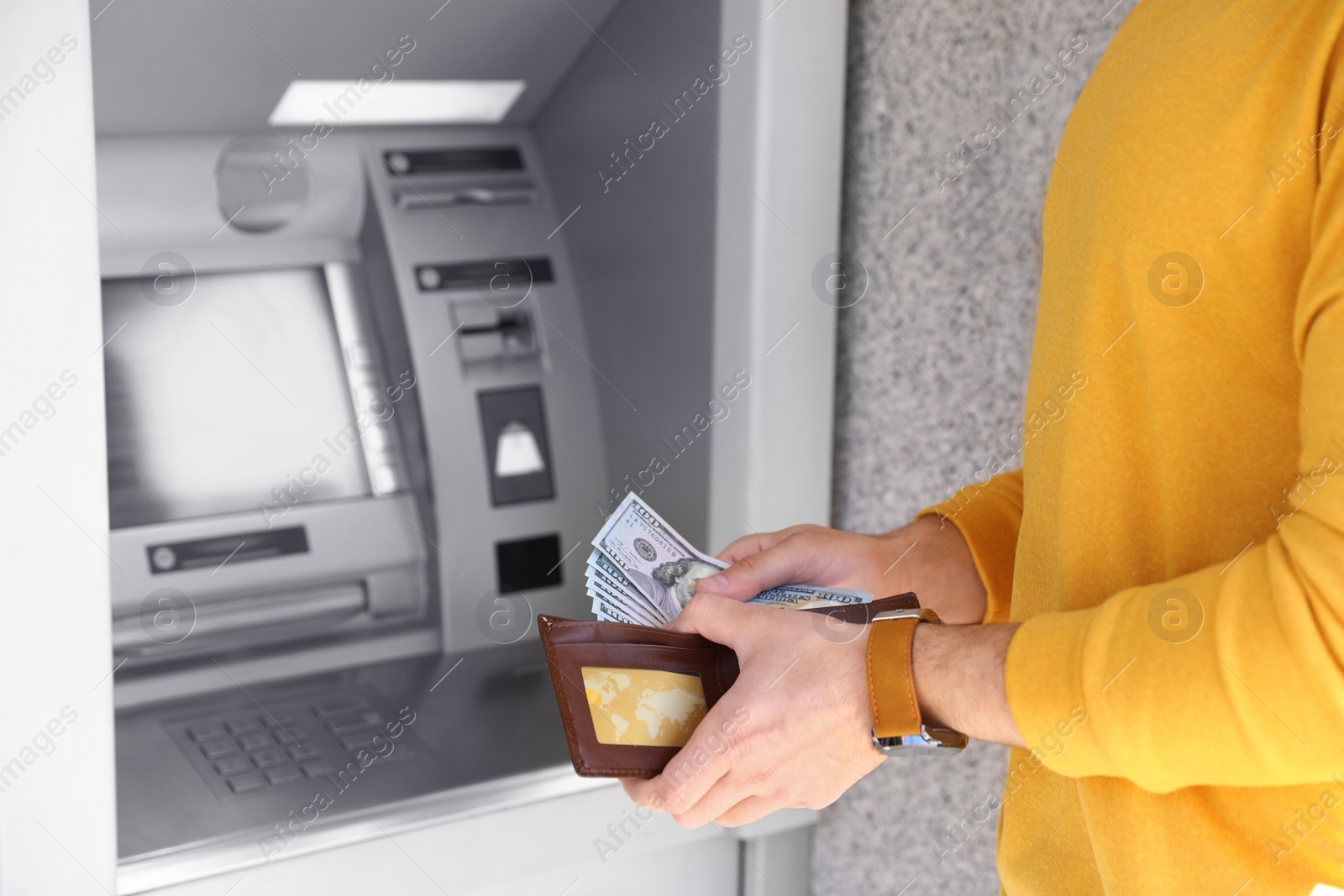 Photo of Young man with money near cash machine outdoors, closeup