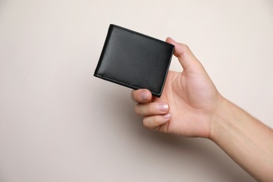 Photo of Man holding black leather wallet on light background, closeup. Space for text