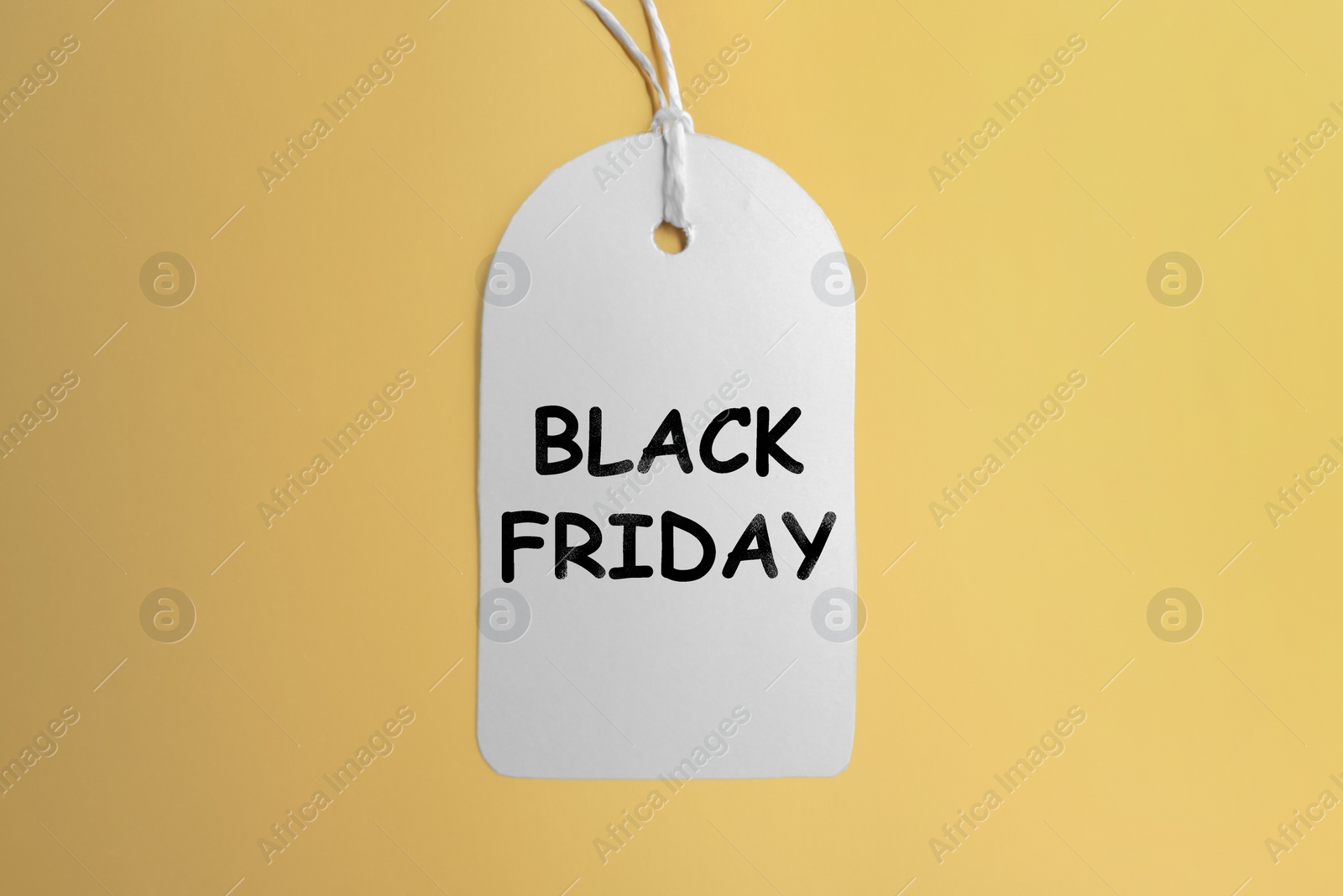 Photo of White blank tag on golden background, top view. Black Friday concept