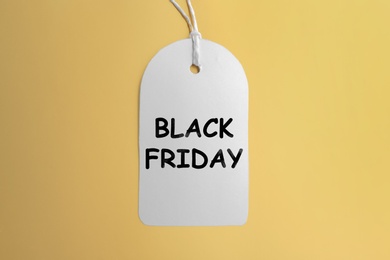 White blank tag on golden background, top view. Black Friday concept