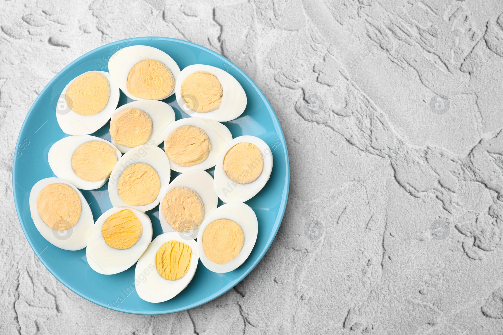Photo of Fresh hard boiled eggs on light grey textured table, top view. Space for text