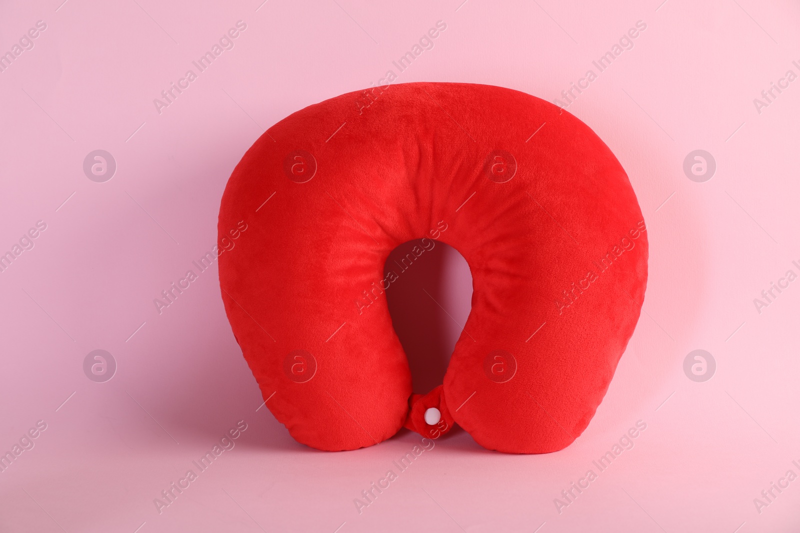 Photo of One red travel pillow on pink background