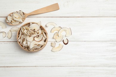 Photo of Tasty coconut chips on white wooden table, flat lay. Space for text