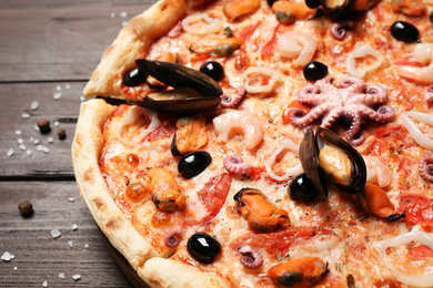 Photo of Tasty pizza with seafood on wooden table, closeup
