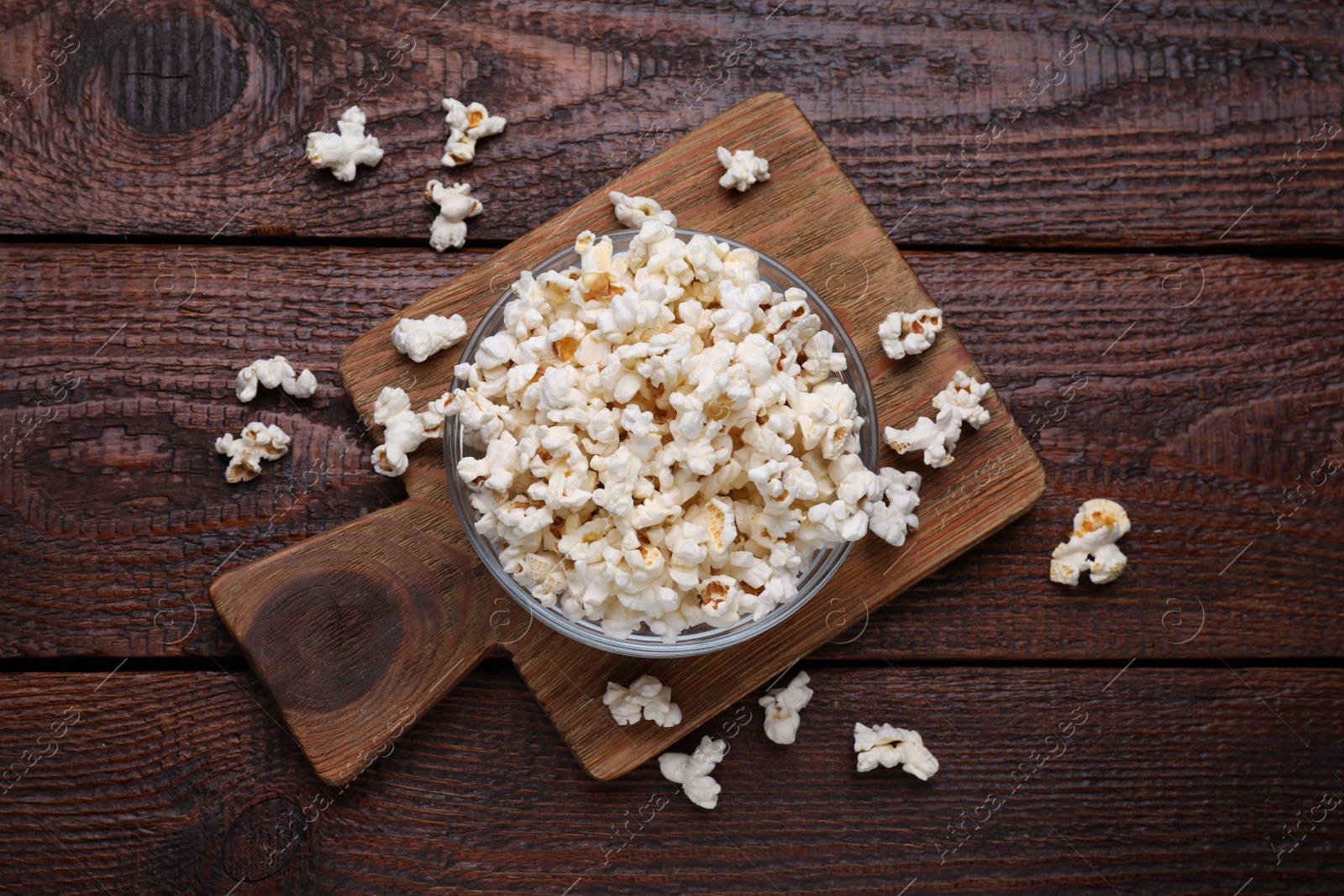 Photo of Bowl of tasty popcorn on wooden table, flat lay