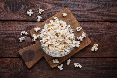Bowl of tasty popcorn on wooden table, flat lay