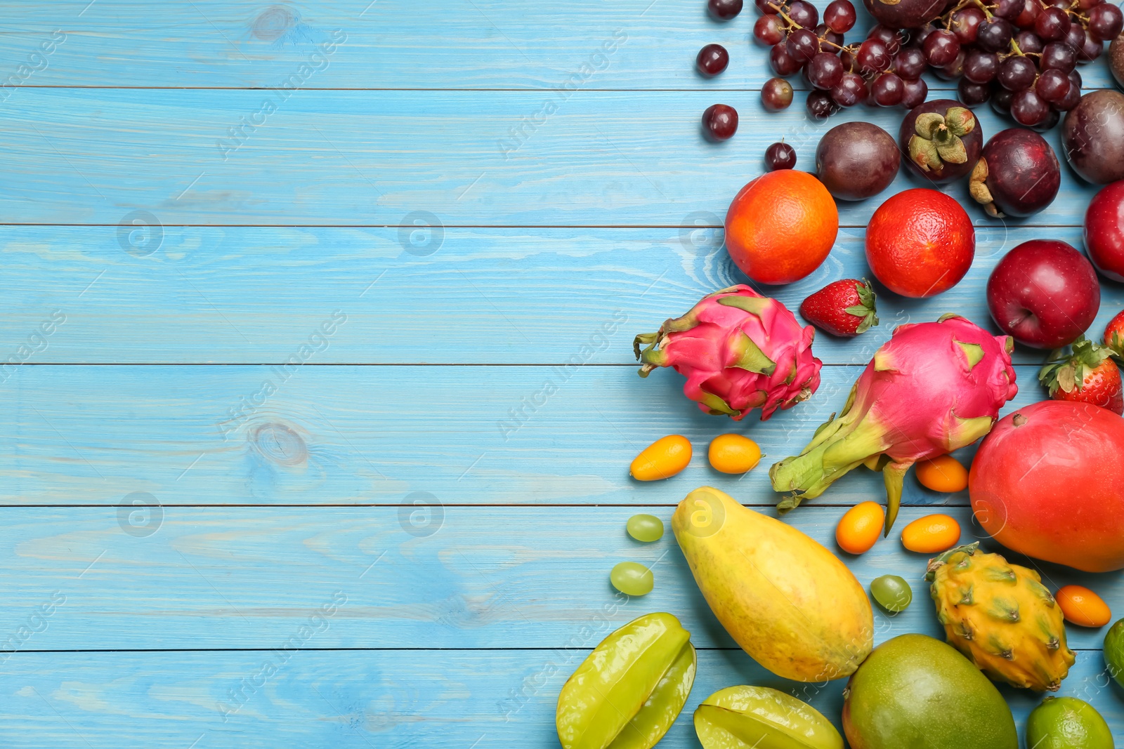 Photo of Many different delicious exotic fruits on blue wooden table, flat lay. Space for text