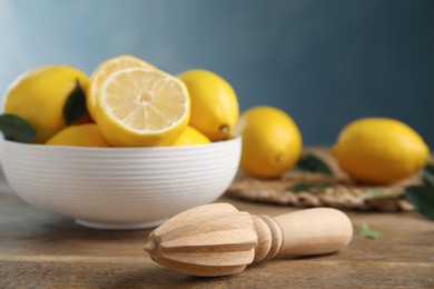 Photo of Squeezer with lemons on wooden table, closeup