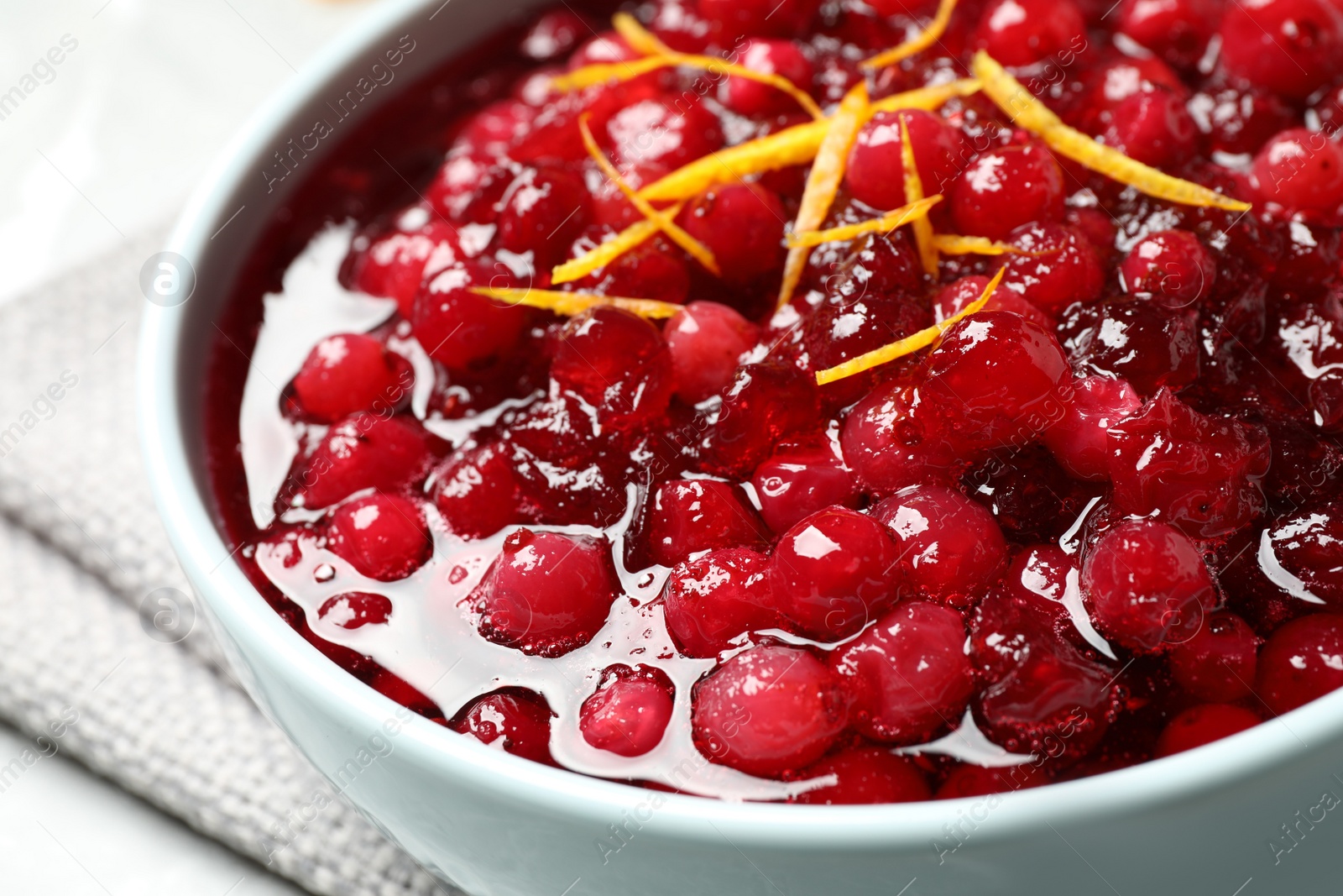 Photo of Fresh cranberry sauce with orange peel in bowl, closeup