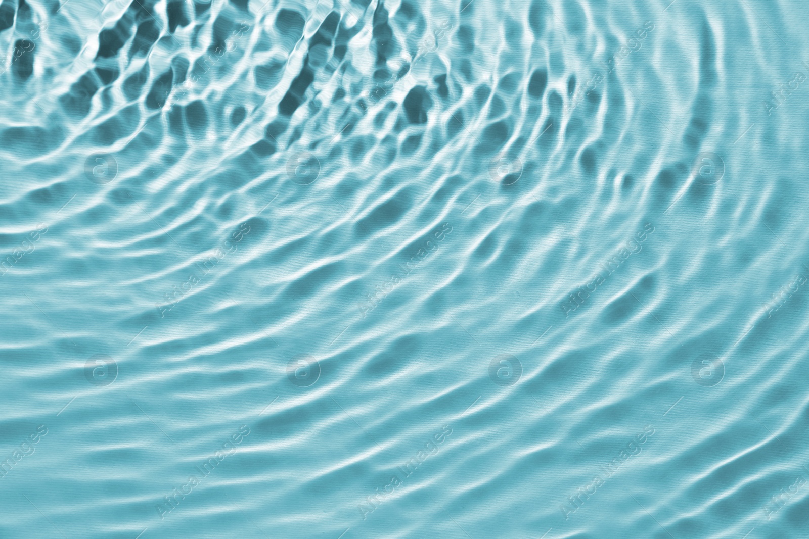 Image of Rippled surface of clear water on light blue background, closeup