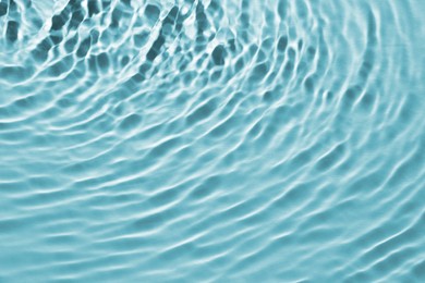 Rippled surface of clear water on light blue background, closeup