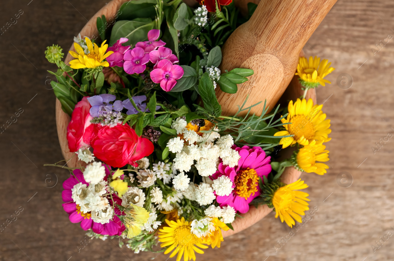 Photo of Mortar, pestle and different flowers on wooden table, top view