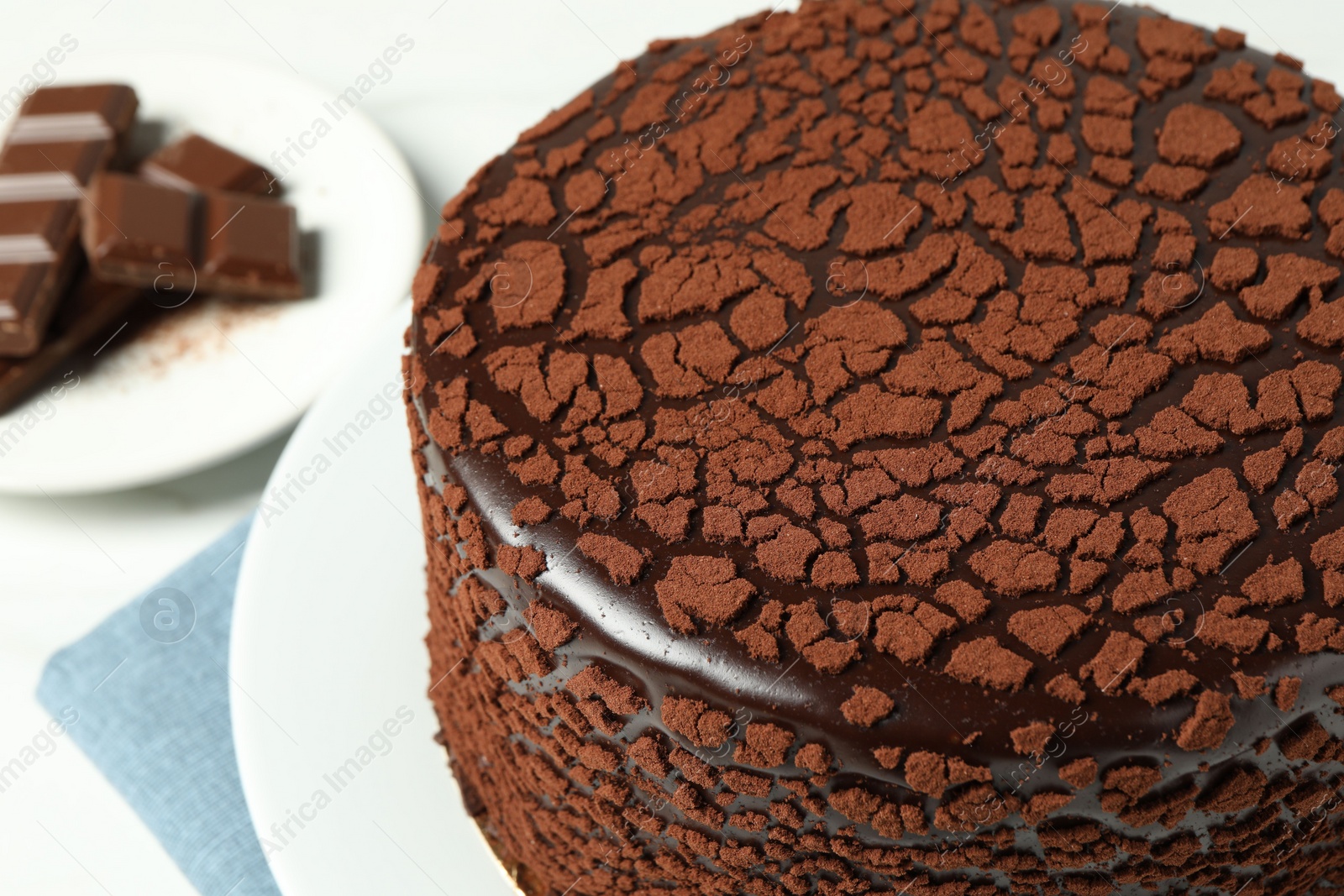 Photo of Delicious truffle cake and chocolate pieces on white table, closeup